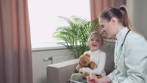 Un medico con un cappotto bianco chiede al bambino cosa lo disturba. Medico di famiglia. — Video Stock