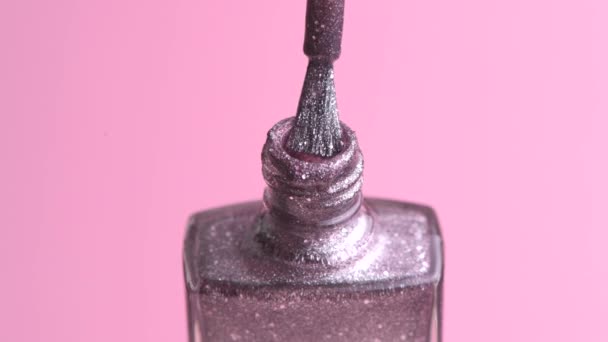 Close-up of beautiful silvery color nail polish with glitter Pink background. — Stock Video
