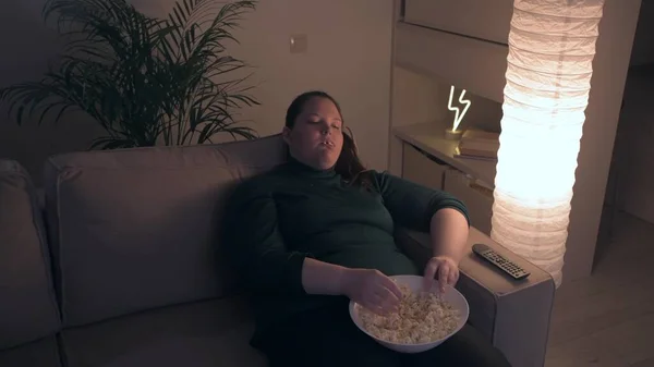 Langweiliger Film. Das Mädchen langweilt sich und isst nachts Popcorn. Menschliche Emotionen. 4K — Stockfoto