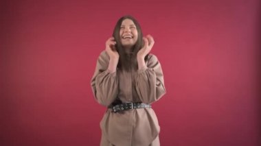 Güzel esmer kız kameraya bakıyor, dans ediyor ve gülümsüyor..