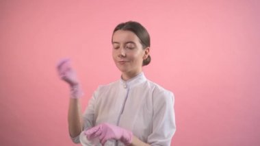 Kız bir güzellik salonunda çalışıyor. Tıbbi pembe eldivenli eller diş ipini tutar.