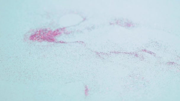 Des étincelles roses gisent sur la surface bleue et un pinceau cosmétique tombe dessus. — Video