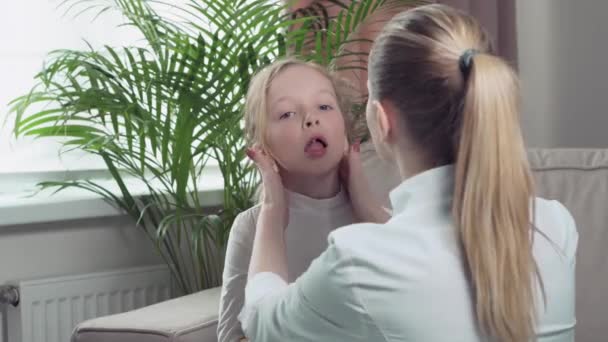 A girl shows a sore throat to a doctor by opening her mouth. — Stock Video