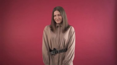 Güzel, mütevazı bir kız gülümser ve utanır. Kırmızı arkaplan.