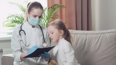 Kadın doktor hasta bir kızı sorguluyor ve bir dosyaya bilgi yazıyor..