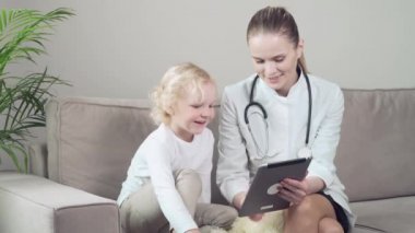 Genç bir kadın doktor tablette bir çocuk çizgi filmi gösteriyor..