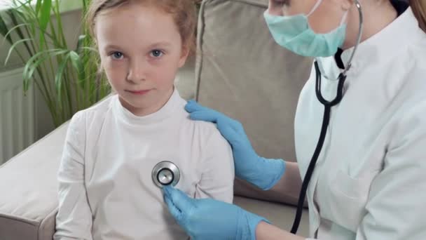 Una chica sentada en un sofá escucha lo que dice el médico. La chica tiene un resfriado. . — Vídeos de Stock