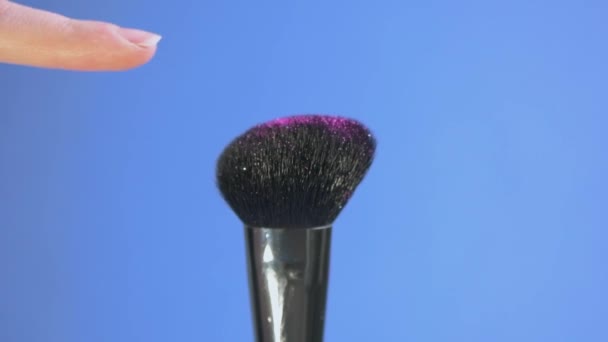 A finger touches a pink sparkle cosmetic brush. Slow motion. — Stock Video