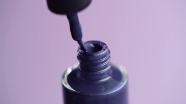 Close-up van een vrouw hand opent een pot donker gekleurde nagellak. — Stockvideo