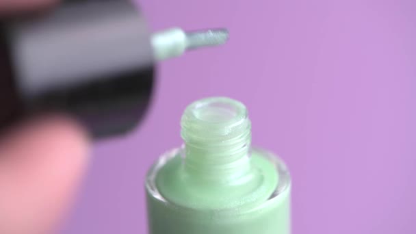 Een vrouw hand opent een pot groene nagellak met glitter. — Stockvideo