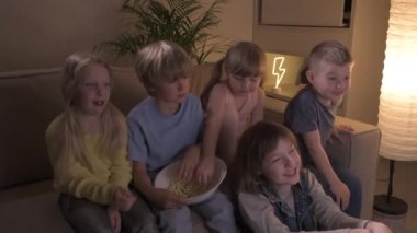 Bir grup şirin çocuk en sevdikleri çizgi filmi birlikte izleyip gülüyorlar..