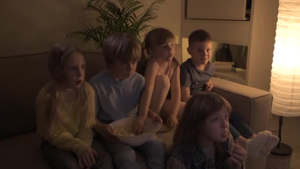 Cinco niños encantadores están viendo una película de terror en la oscuridad, asustados . — Vídeo de stock