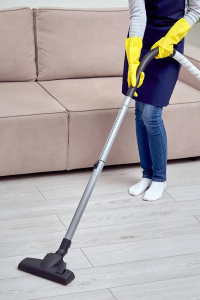 A rapariga do serviço de limpeza limpa a casa. Menina em luvas e um avental — Fotografia de Stock