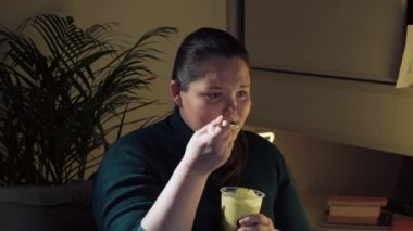 Üzgün bir kız TV 'de romantik bir melodram izliyor ve tatlı dondurma yiyor..