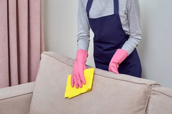 Девушка в розовой перчатке моет диван желтой тряпкой для чистки . — стоковое фото
