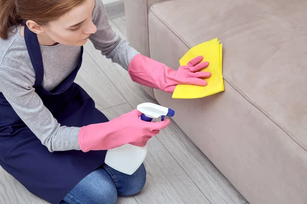 A menina aplica um agente de limpeza, produtos químicos domésticos para o mobiliário . — Fotografia de Stock