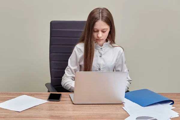 Joven hermosa chica morena está sentado en la oficina con un ordenador portátil . — Foto de Stock