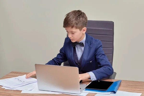 Schöner junger Mann sitzt in einem Stuhl und arbeitet an einem Laptop. — Stockfoto