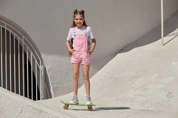 키가 날씬 한 한 소녀는 미소를 지으며 스케이트 보드를 탄다. 여름 방학. — 스톡 사진
