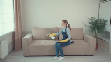 Kız güzel, rahat bir odada kanepeye oturur ve döşenmiş mobilyaları yıkar..