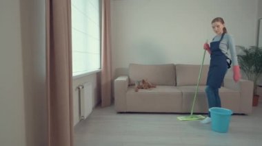 Tatlı bir kız oturma odasını temizliyor ve dans ediyor. Yerleri sil..