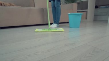 Oturma odasındaki paspasın yakın çekimi. Yakınlarda su dolu bir kova var..