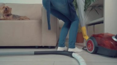 Kız elektrik süpürgesini fişe takıyor ve elektrik süpürgesi çekiyor. Günlük rutin.