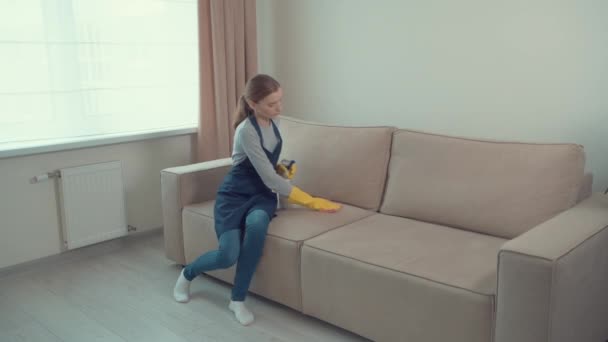 Seorang gadis muda mencuci noda kotor di sofa ringan. Pembersihan rumah. — Stok Video