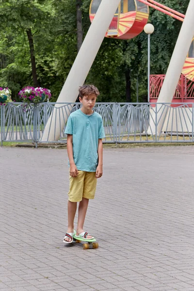 Um adolescente está montando um skate no parque de diversões em um dia quente de verão . — Fotografia de Stock