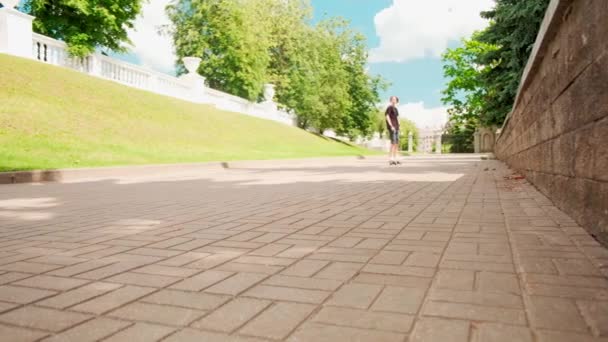 ハンサムな男が前方の道路上のスケートボードに乗っています。夏休み. — ストック動画