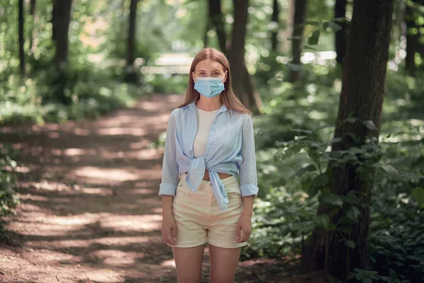 Hermosa joven en una máscara médica en el parque. —  Fotos de Stock