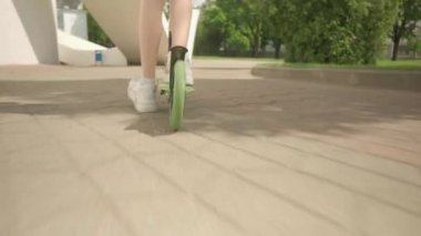 Uzun saçlı, parkta scooter süren güzel bir kız..