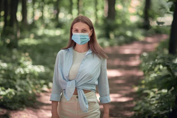 La chica camina en el parque en el verano con una máscara médica. —  Fotos de Stock