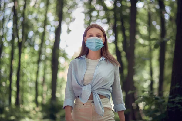 Protección durante una pandemia. Chica joven con una máscara médica en el parque. —  Fotos de Stock