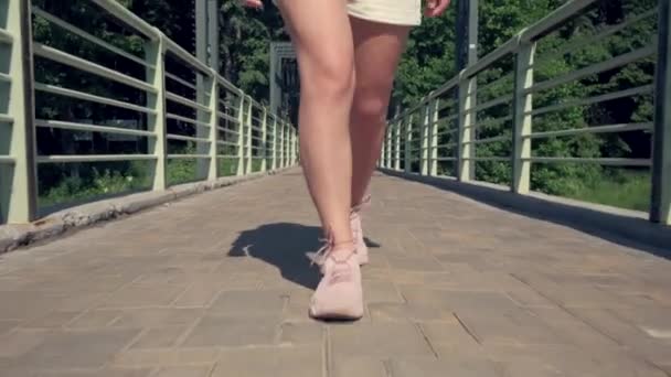 Köprüde şortla yürüyen ince bacaklar. Sıcak yaz günü. 4K video. — Stok video
