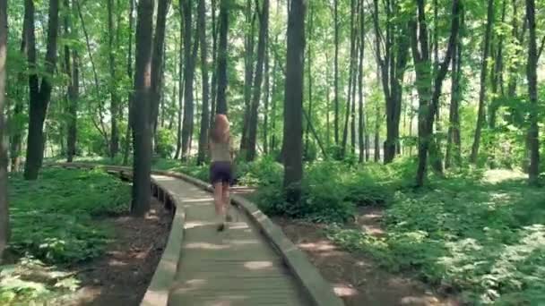 Buitensporten. Een meisje met slanke benen in korte broek loopt in het park. — Stockvideo