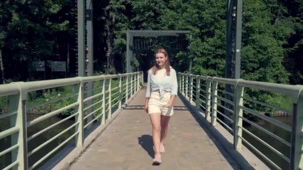 Usmívající se krásná dívka kráčí přes most a má výhled. Video 4K. — Stock video