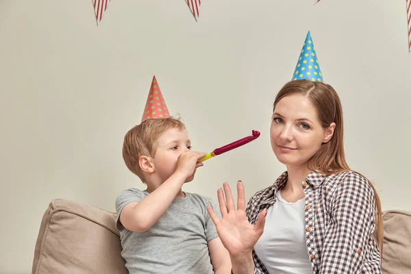 Sonen blåser in i verktyget och tittar på mamma. Mamma gör en gest, tittar på kameran — Stockfoto