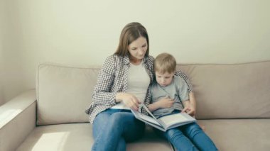 Anne çocuğu okula hazırlar ve evde otururken oğluyla kitap okur..