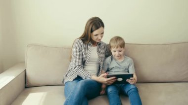Genç ve modern bir anne çocuğuna online tablet kullanmayı öğretiyor. 4k