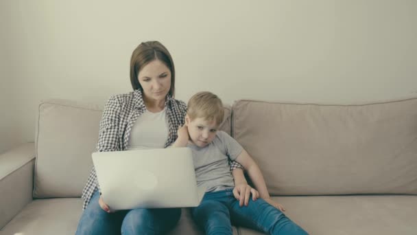 Anne ve bebek kanepede birlikte oturur ve birlikte eğitici bir film izlerler.. — Stok video