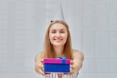 Mutlu gülümseyen güzel kız bir hediye veriyor. Gülümsüyor ve kameraya bakıyor.