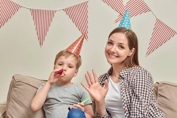 Den lille pojksonen blåser in i verktyget. Mamma ler och tittar på kameran. — Stockfoto