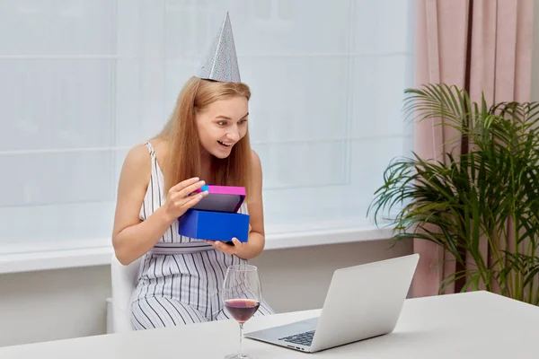 Celebrando un cumpleaños delante de una webcam. Chica con un regalo en sus manos. —  Fotos de Stock