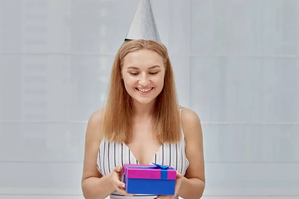 Feliz sonrisa hermosa chica sosteniendo un regalo en una caja brillante en su mano. —  Fotos de Stock