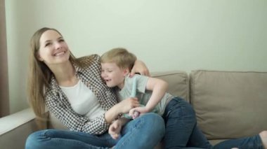 Anne ve bebek evde kanepede otururken yumuşak bir oyuncakla oynuyorlar..