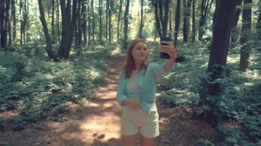 Genç ve güzel bir kadın yolda yürürken selfie çekiyor. 4k