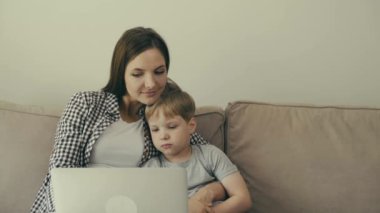 Anne ve oğlu birlikte kanepede oturup çizgi film izliyorlar..