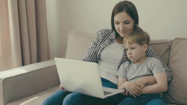 Eine junge Mutter und ihr Kind schauen gemeinsam einen Lehrfilm oder Zeichentrickfilm. — Stockvideo