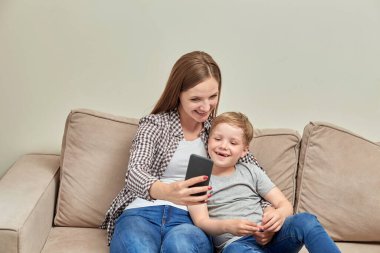 Genç, güzel anne oğlunun yanında otururken internetten iletişim kuruyor..